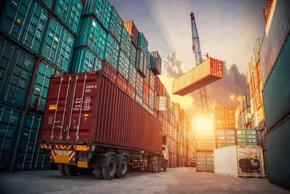 Container yard at sunset with a crane loading a shipping container
